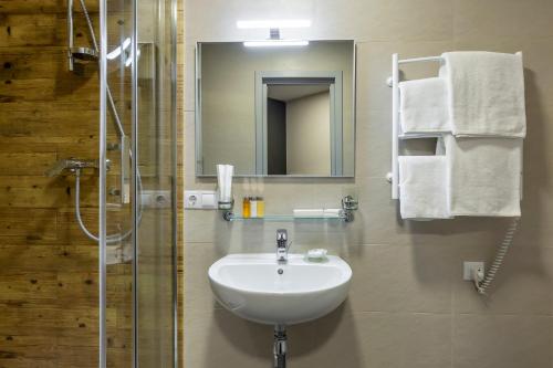 a bathroom with a sink and a shower with a mirror at Favor Sport Hotel in Kyiv