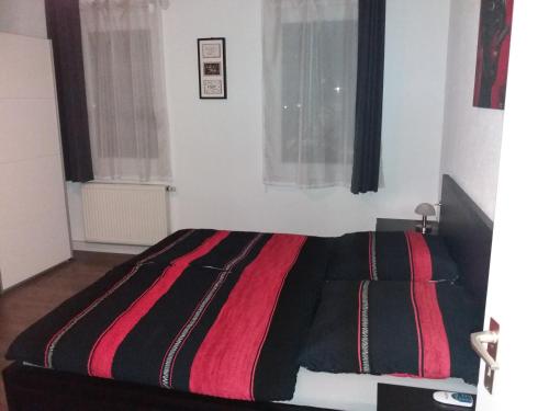 Schlafzimmer mit einem Bett mit einer roten und schwarzen Decke in der Unterkunft Schwäbisch Gmünd Stadtmitte in Schwäbisch Gmünd