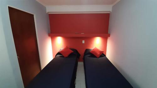 2 camas en una habitación con paredes rojas en Departamento cómodo, muy iluminado y bien ubicado. en Paraná