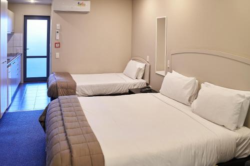 a hotel room with two beds and a kitchen at Azena Suites & Apartment in Christchurch