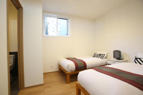 1 dormitorio con 2 camas y ventana en Apartments Hakuba, en Hakuba