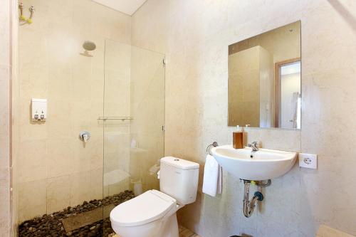 Un baño con inodoro, lavabo y espejo. en Askara Villa Uluwatu, en Uluwatu