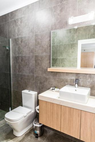 a bathroom with a toilet and a sink and a mirror at Lakes and Ocean Hotel Forster in Forster