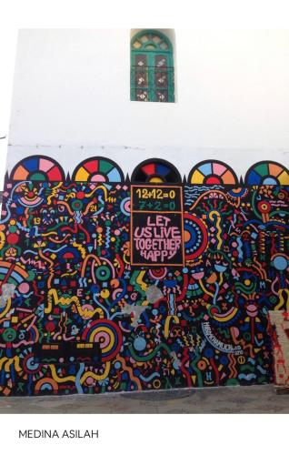 a wall covered in graffiti with a sign on it at TANGER/ASILAH: APPART 50m2 FACE MER ET PISCINES, 5 PLACES, TOUT ÉQUIPÉ+WIFI+CLIM in Briech