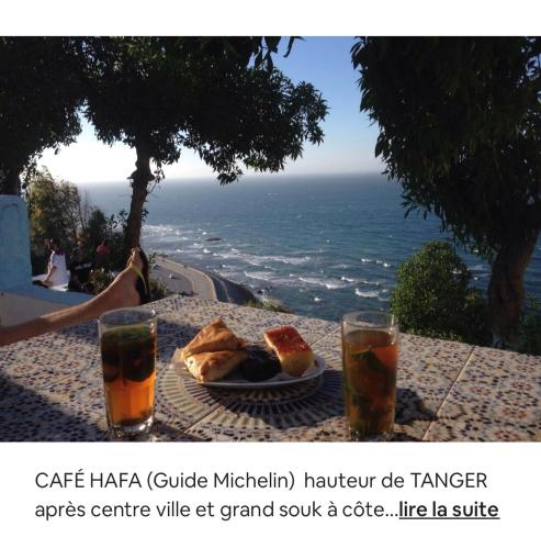 a table with a plate of food and two glasses at TANGER/ASILAH: APPART 50m2 FACE MER ET PISCINES, 5 PLACES, TOUT ÉQUIPÉ+WIFI+CLIM in Briech