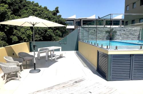 um pátio com uma mesa, um guarda-sol e uma piscina em Heart of Manly Apartment em Sydney