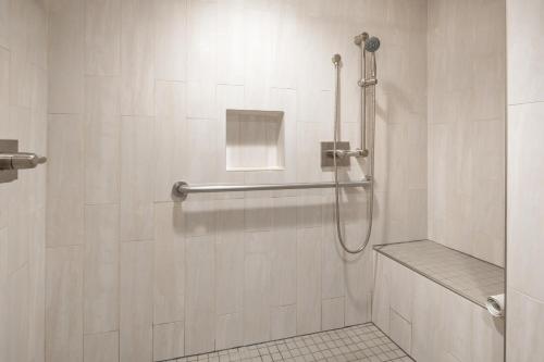 y baño con ducha y azulejos blancos. en Atherton Park Inn and Suites, en Redwood City