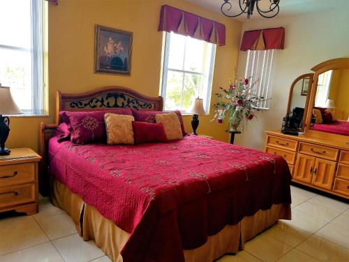 a bedroom with a large bed with a red bedspread at My Florida Lake House in Homestead