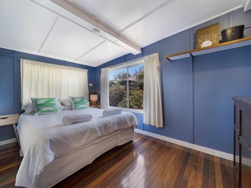 a blue bedroom with a large bed and a window at Ahoy Cottage by Discover Stradbroke in Point Lookout