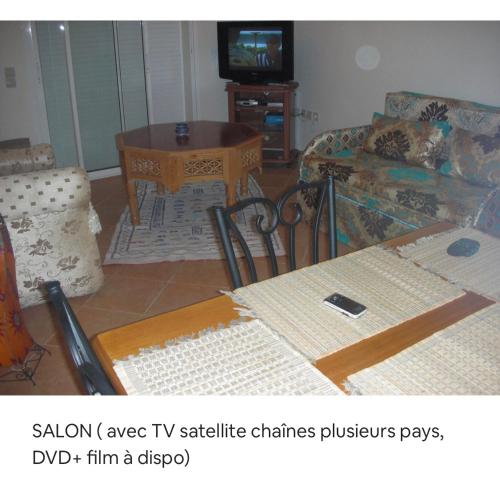a living room with a couch and a table with a cell phone on it at TANGER/ASILAH: APPART 50m2 FACE MER ET PISCINES, 5 PLACES, TOUT ÉQUIPÉ+WIFI+CLIM in Briech