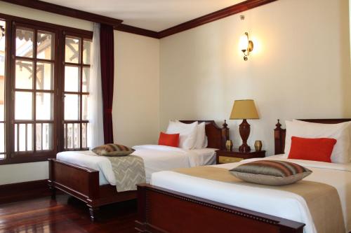 a hotel room with two beds and two windows at Templation Residence in Siem Reap