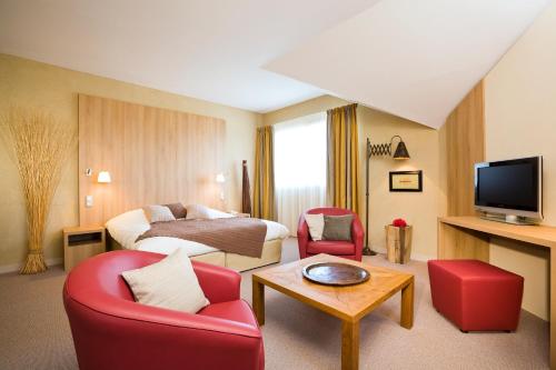 a hotel room with red chairs and a bed at ibis Styles Cholet in Cholet