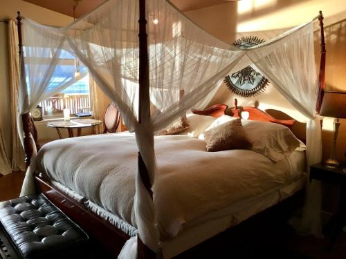 um quarto com uma cama de dossel e redes mosquiteiras em The Tuwanek Hotel and Spa em Sechelt