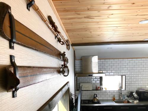 a kitchen with a wall with wooden ceilings and a sink at Ryder's House with Free use of 4W car in Hakuba