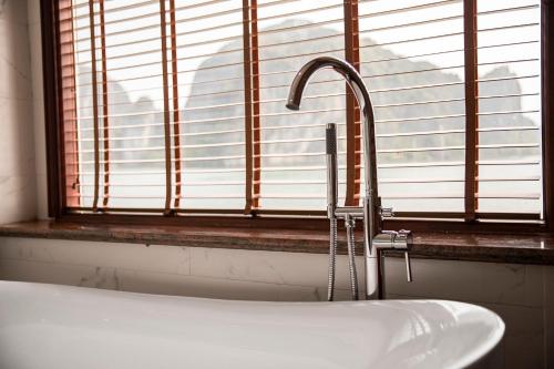 a bathroom sink with a faucet in front of a window at Dora Cruise by HAG in Ha Long