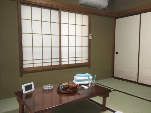 Zimmer mit einem Holztisch und 2 Fenstern in der Unterkunft Hamayuu in Higashiizu