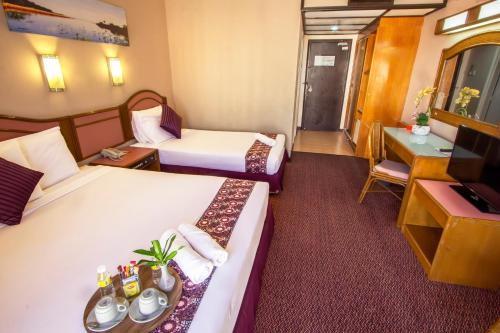 a hotel room with two beds and a television at Hotel Grand Continental Langkawi in Kuah