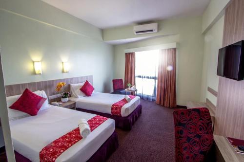 a hotel room with two beds and a television at Hotel Grand Continental Langkawi in Kuah