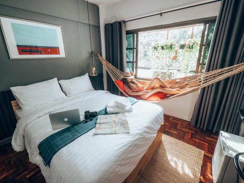 a woman laying in a hammock in a bedroom at Haus Sathorn 11 Residence in Bangkok