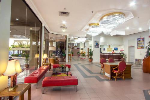 a lobby of a hospital with red couches and chairs at Hotel Grand Continental Langkawi in Kuah