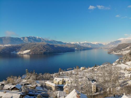 a view of a lake with snow covered mountains at Frühstückspension Götzfried-Hof in Millstatt