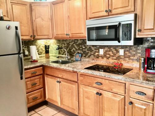 a kitchen with wooden cabinets and a sink and a microwave at Da Kona West 305 in Kailua-Kona