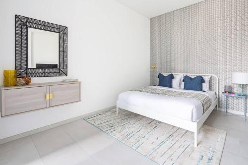 a white bedroom with a bed and a mirror at Frank Porter - Marquise Square in Dubai
