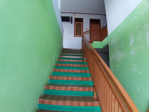 a staircase in a building with green walls and wooden railings at OYO Life 2884 Wisma Jatnika Syariah in Kuningan