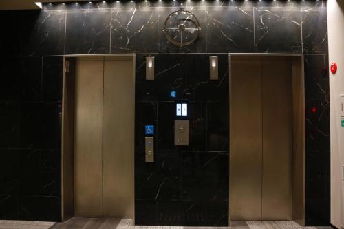 two elevators in a building with black tile at PORTA INN bentencho in Osaka