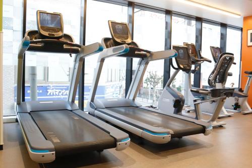 a gym with three treadmills in a room with windows at PORTA INN bentencho in Osaka