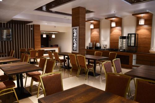 SītāpurMayur Hotel & Resort的有木桌椅和酒吧的餐厅