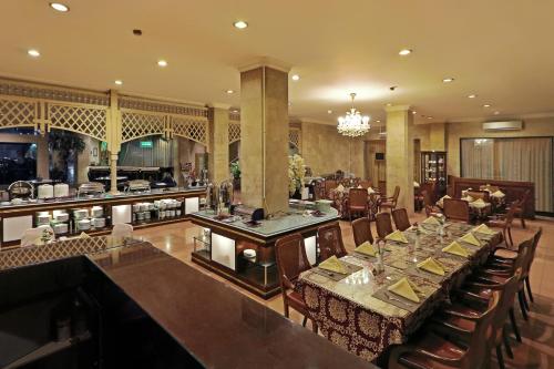 a dining room with a long table and a restaurant at Hotel Indah Palace Solo in Solo