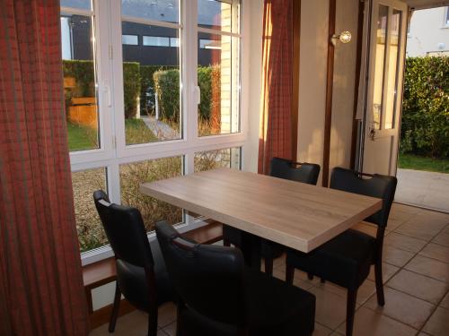 une table et des chaises dans une pièce avec une fenêtre dans l'établissement Maisonnette LE COTTAGE à 50m DE LA PLAGE d'Asnelles , 3km d'Arromanches, 10km de Bayeux, à Asnelles