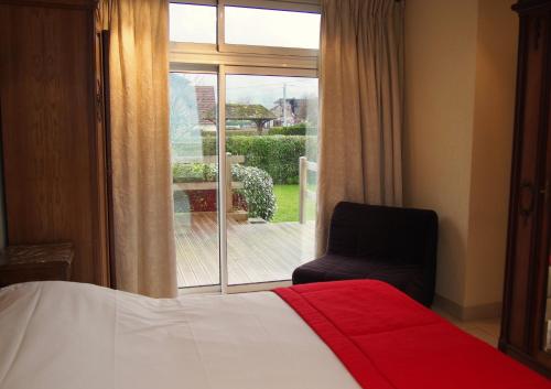 a bedroom with a bed and a chair and a window at Gîtes "Plage" ou "Pieds dans l'Eau" en FRONT DE MER à Asnelles , 3km d'Arromanches, 10km de Bayeux in Asnelles
