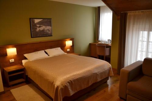 a bedroom with a bed and a chair and a window at B&B Villa Panuka in Pančevo