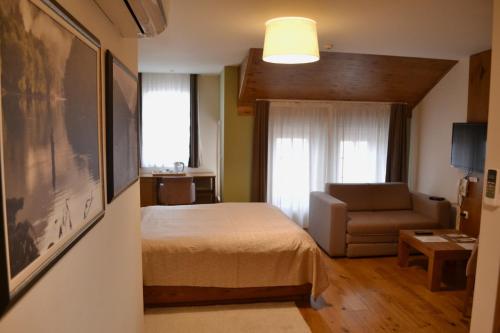 a bedroom with a bed and a couch and a window at B&B Villa Panuka in Pančevo
