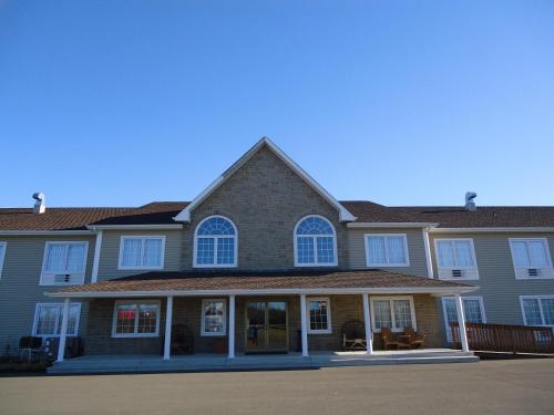 a large brown house with white windows on it at Auberge Bouctouche Inn & Suites in Bouctouche