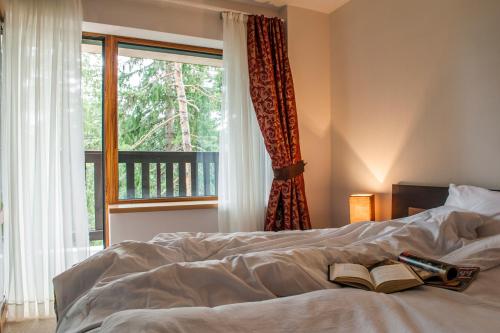 ein Schlafzimmer mit einem Bett mit einem Buch und einem Fenster in der Unterkunft Pamporovo Central Apartments in Pamporowo