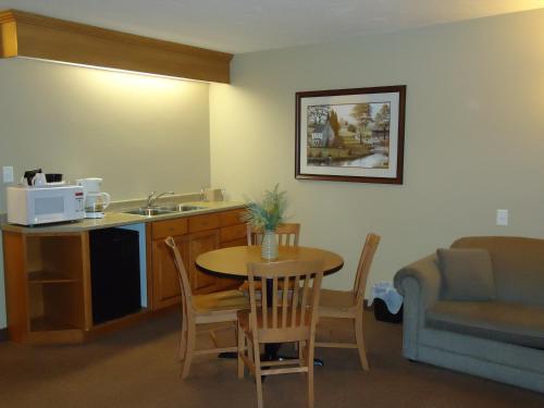 a kitchen with a table and chairs and a refrigerator at Auberge Bouctouche Inn & Suites in Bouctouche