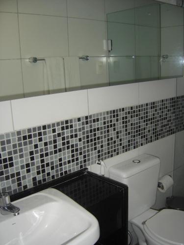 a bathroom with a toilet and a sink and a mirror at Bianca Praia Hotel in Recife