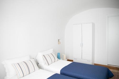a bedroom with a white bed and a blue blanket at IseoLakeRental - Borgo Lago in Riva di Solto