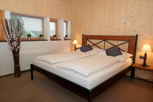 a bedroom with a large bed with white sheets at HT Chalets Harrachov in Harrachov
