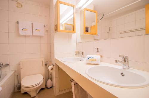 Baño blanco con lavabo y aseo en Rothornblick 41 by Arosa Holiday, en Arosa