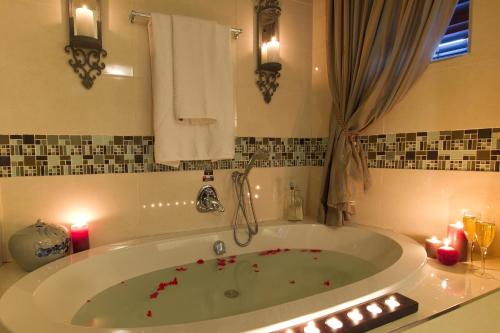 a bathroom with a large tub with candles in it at Arum Place Guest House in Johannesburg