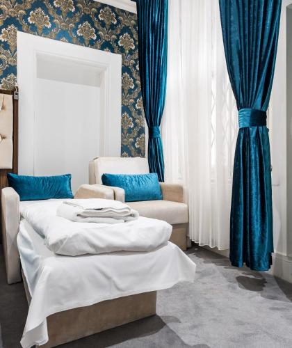 two beds and a chair in a room with blue curtains at Vilenza Hotel in London