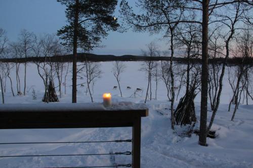 a candle sitting on a bench in the snow at Villa Váibmu in Inari
