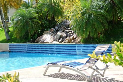 uma cadeira ao lado de uma piscina com uma fonte em Sunrise Villa em Maunabo