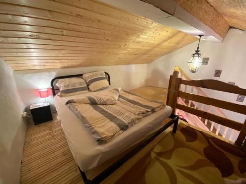 a bed in a small room with a wooden ceiling at Maison Carmen - Restaurant , meublé de tourisme, appartements in Xertigny