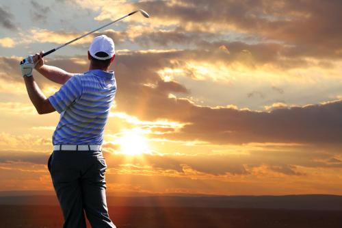 a man swinging a golf club at the sunset at The Waterfront Inn in Westward Ho