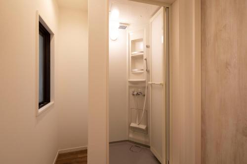 a hallway with a door leading to a room with shelves at Hotel Litlle Bird OKU-ASAKUSA in Tokyo